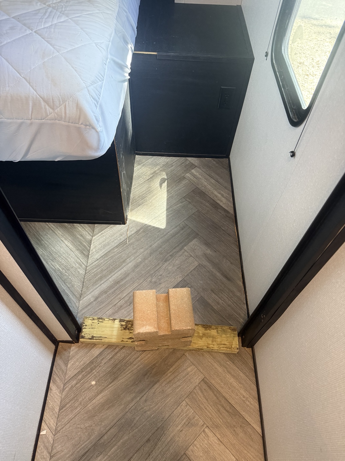 Existing linoleum returned beside the bed; temporary weights remain in place.